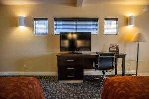 Habitación con escritorio, TV y silla. en Marinwood Inn & Suites en Novato