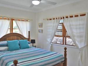 a bedroom with a bed with blue pillows and a window at Cuddles Cottage 4 Christmas Bush Avenue - holiday house near Dutchies in Nelson Bay
