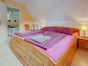 a large wooden bed with purple sheets in a bedroom at Stylish Apartment in Merschbach near the Forest in Merschbach