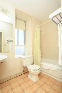 a bathroom with a toilet and a sink and a tub at Royal Inn and Suites at Guelph in Guelph