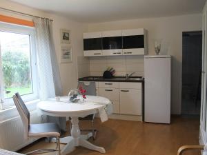 a kitchen with a white table and a white refrigerator at Apartment in Pepelow with Roofed Terrace, Garden, Barbecue in Pepelow