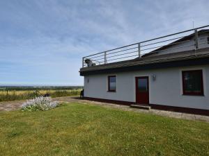 ein weißes Haus mit einer roten Tür auf einem Feld in der Unterkunft Bastorf Sea View Escape in Bastorf