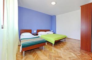 two beds in a room with blue walls and wooden floors at Apartments Sorić in Bibinje
