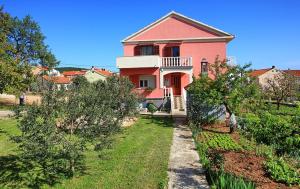 a large pink house with a garden in front of it at Apartments Sorić in Bibinje