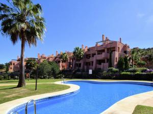 a swimming pool in front of a building with a palm tree at Belvilla by OYO El Soto de Marbella in Ojén