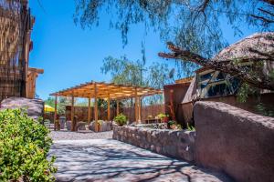 un giardino con pergolato in legno e parete in pietra di San Pedro Domos a San Pedro de Atacama Altre 37 foto
