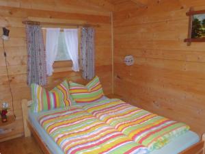 シュタインガーデンにあるLog cabin in Bavaria with covered terraceのカラフルな枕が備わるログキャビンのベッド1台分です。
