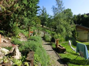 einen Garten mit einem Zaun und einem Stuhl im Gras in der Unterkunft Log cabin in Bavaria with covered terrace in Steingaden