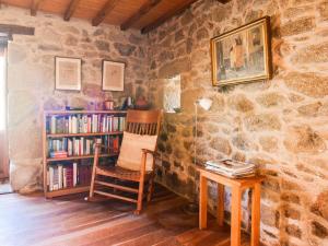 um quarto com uma cadeira e uma estante de livros com livros em Belvilla by OYO Casa Ribeira Sacra em Castillón