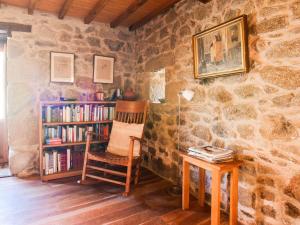 a room with a chair and a book shelf with books at Belvilla by OYO Casa Ribeira Sacra in Castillón