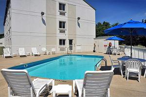 a pool with chairs and umbrellas next to a building at Motel 6-Milan, OH - Sandusky in Milan