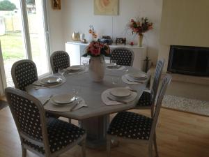 uma mesa de jantar com cadeiras e um vaso de flores em Seafront holiday home with garden in Denneville em Denneville