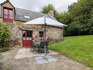 una mesa y sillas con sombrilla frente a un edificio en Charming child friendly holiday home, en La Boussac