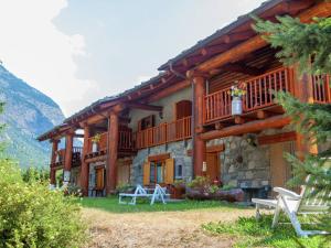 een blokhut met een balkon en tafels en stoelen bij Belvilla by OYO GrBe Penta in Antey-Saint-André