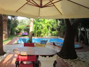 mesa y sillas con sombrilla frente a la piscina en Attractive Villa in Giannoudi with Private Pool en Giannoudi