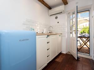 uma cozinha com armários brancos e um frigorífico azul em Adorable holiday home located near the beach em Baska
