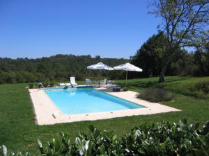una piscina en un patio con sombrillas en Holiday home with tennis court in Montcl ra, en Frayssinet-le-Gélat
