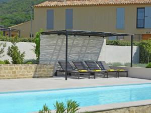 a pool with two lounge chairs and a canopy next to a swimming pool at Vibrant Villa in Malauc ne with Private Garden in Malaucène