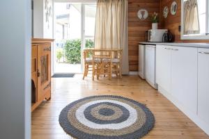 a kitchen with a table and a rug on the floor at Beach Folly - Whitianga in Whitianga