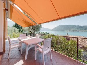 einen Tisch und Stühle auf einem Balkon mit Blick auf das Wasser in der Unterkunft Belvilla by OYO Villa Olivella in Sale Marasino