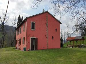a red barn sitting on top of a lush green field at Belvilla by OYO Appartamento Yassine in Tredozio