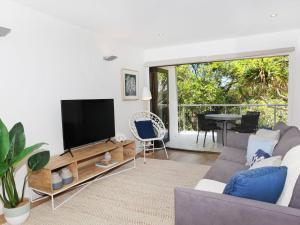 a living room with a couch and a flat screen tv at Windmill 4 Two Bedroom Beachside Apartment on Parkyn Parade in Mooloolaba