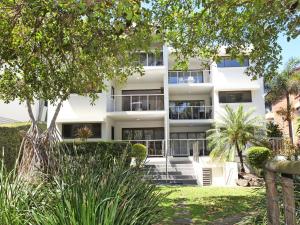 a white apartment building with trees in front of it at Windmill 4 Two Bedroom Beachside Apartment on Parkyn Parade in Mooloolaba