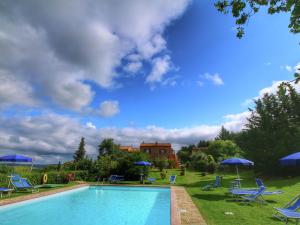 a swimming pool with blue chairs and umbrellas at Belvilla by OYO Casa Tiglio in San Quirico dʼOrcia