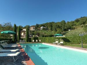 uma piscina com espreguiçadeiras e guarda-sóis em Belvilla by OYO Villa Lonanno em Pratovecchio