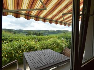 a porch with a table and a view of a field of flowers at Cozy Holiday Home in Boevange Clervaux with Garden in Boevange-Clervaux