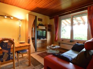 a living room with a couch and a table and a tv at Cozy Holiday Home in Boevange Clervaux with Garden in Boevange-Clervaux