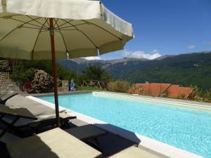 a pool with an umbrella and two chairs and a table with an umbrella at Belvilla by OYO Chalet Appennino in Cutigliano
