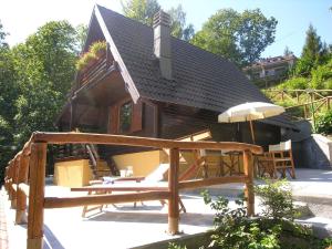 a house with a deck and an umbrella at Belvilla by OYO Chalet Appennino in Cutigliano