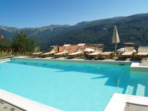a large swimming pool with chairs and umbrellas at Belvilla by OYO Chalet Appennino in Cutigliano