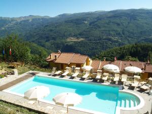 a swimming pool with chairs and umbrellas and mountains at Belvilla by OYO Chalet Appennino in Cutigliano
