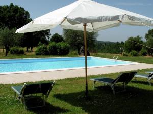 um guarda-sol branco e duas cadeiras ao lado de uma piscina em Belvilla by OYO Piano em Sorano