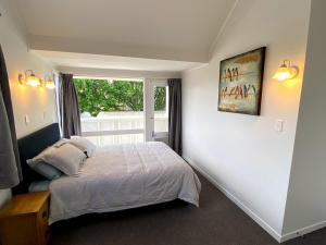 a bedroom with a bed and a window at Chamberlain House - 3 bedroom house by Manly beach in Auckland