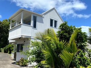 a white house with palm trees in front of it at Chamberlain House - 3 bedroom house by Manly beach in Auckland