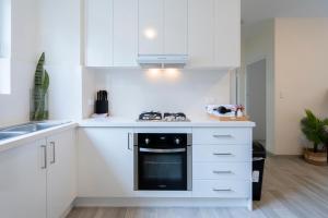 a kitchen with white cabinets and a stove top oven at Lotus Stay Manly - Apartment 29B in Sydney +9 photos