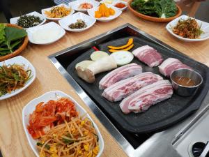 a table with a tray of meat and vegetables at Sea Dragon Pension in Seogwipo +16 photos