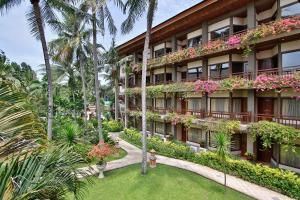 an exterior view of a hotel with flowering plants and palm trees at Jayakarta Hotel Lombok in Senggigi
