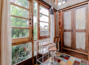 a room with a table and a chair and windows at Lorong Homestay in Bantul