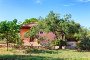 a pink house with trees in front of it at Lithies Farm Houses in Vasilikos