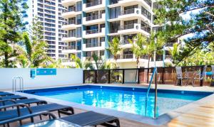 a swimming pool with chairs and a building at Berkeley on the Beach in Gold Coast