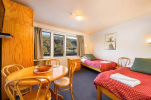 a room with two beds and a table and chairs at Kasees Apartments & Mountain Lodge in Thredbo