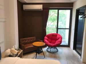 ein Schlafzimmer mit einem roten Stuhl, einem Tisch und einem Fenster in der Unterkunft Chi Chu B&B in Taitung