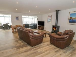 a living room with two leather chairs and a fireplace at Golygfa Ynys Island View in Amlwch