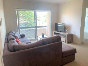 a living room with a brown couch and a television at Silvana Court 3 neat unit with air conditioning in Shoal Bay