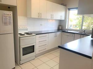 a kitchen with white cabinets and a white stove top oven at Silvana Court 3 neat unit with air conditioning in Shoal Bay