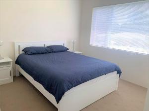 a bedroom with a bed with a blue comforter and a window at Silvana Court 3 neat unit with air conditioning in Shoal Bay
